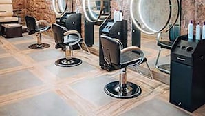 Un salon de coiffure doté de plusieurs postes de travail, chacun comprenant un miroir et un fauteuil.