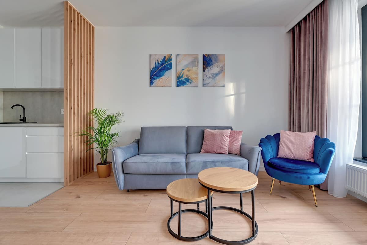 Ein modernes Wohnzimmer mit einem grauen Sofa, einem blauen Sessel und einem kleinen Holztisch.