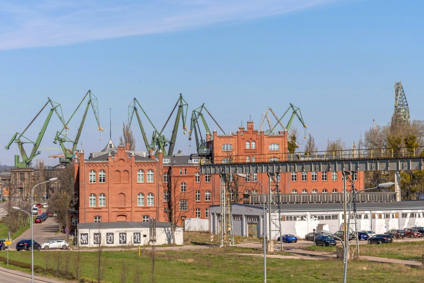 Un grand bâtiment en briques rouges, doté de nombreuses fenêtres et surmonté d’un pont.