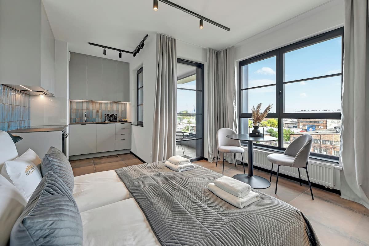 Ein modernes Hotelzimmer mit einem großen Bett, einer Essecke und Blick auf die Stadt.