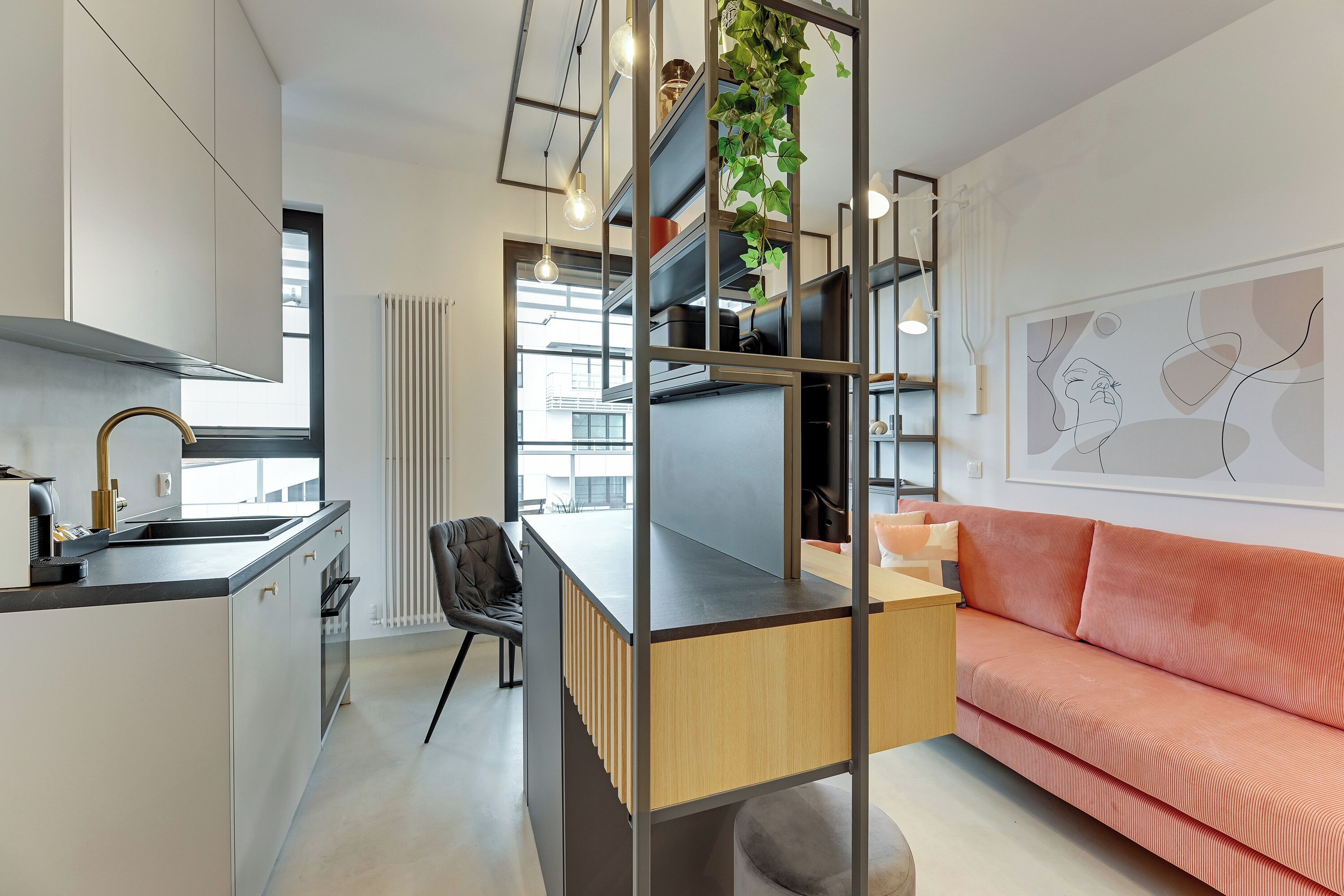 Una cocina moderna con una isla integrada, un comedor con una silla negra y un sofá rojo.