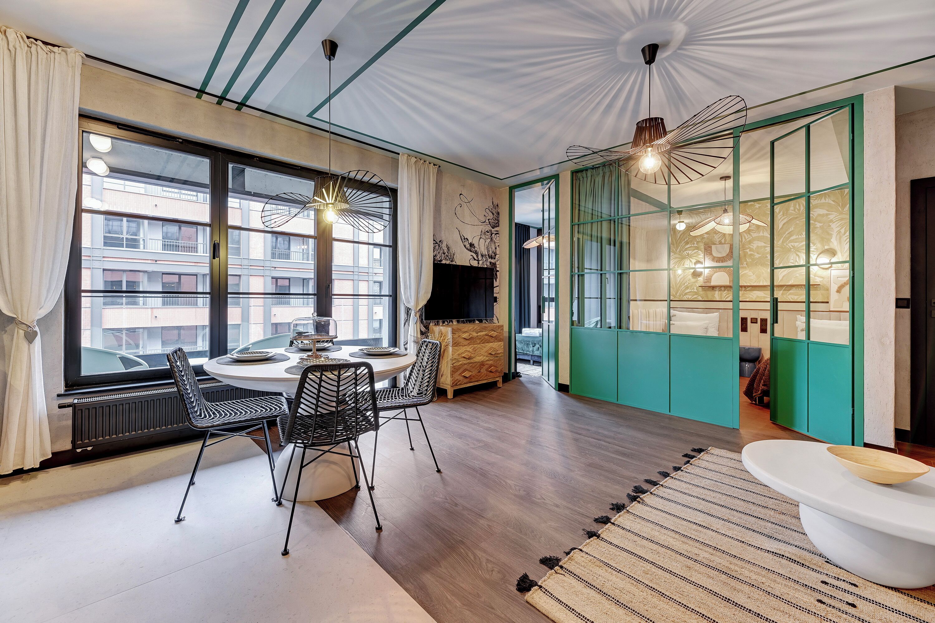 A modern living room with a dining area, large windows, and a view of the cityscape.