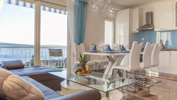 A modern living room with a glass coffee table, a sofa, and a dining area with a table set for six. - Spacious Novi Vinodolski Apartments With Terrace and Shared Pool (Crikvenica)