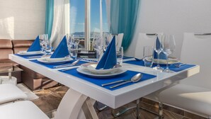 A dining table set for four with blue napkins, white plates, and clear glasses. - Spacious Novi Vinodolski Apartments With Terrace and Shared Pool (Crikvenica)