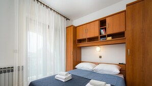 A bedroom with a bed, wooden wardrobe, and a radiator. - Graceful Apartment With Barbecue Area (Porec)