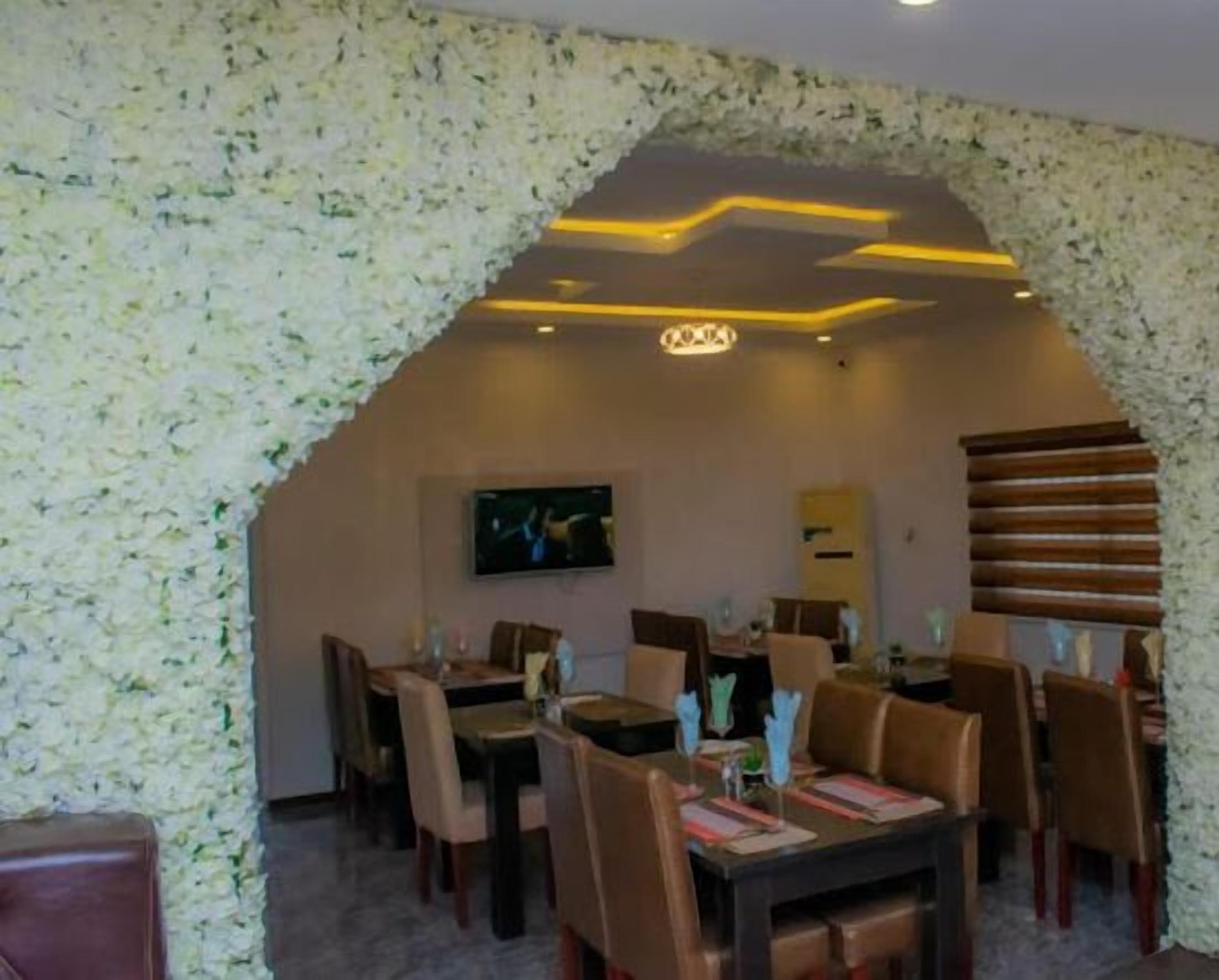 A dining area with a high ceiling, floral wallpaper, and a modern light fixture.