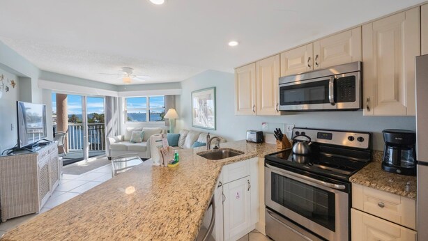 A modern kitchen with granite countertops, stainless steel appliances, and a view to the outside.