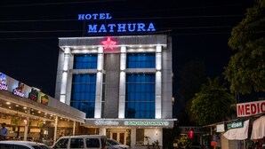 A hotel named 'Hotel Mathura' with a prominent sign, a 'Pure Veg Restaurant' below, and various other shops around. - Hotel Mathura Inn (Rahata)