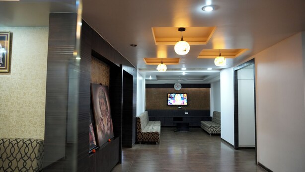 A lobby with a reception desk, seating area, and a television screen. - Hotel Mathura Inn (Rahata)
