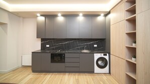 Eine kompakte Küche mit integrierten Geräten, Holzregalen und einer Marmor-Spritzschutzwand.