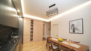 Eine moderne Küche mit schwarzem Arbeitsplatz, Holzschränken und einem Essbereich mit Holztisch und Stühlen.