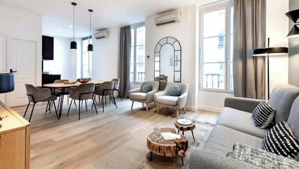 Ein modernes Wohnzimmer mit einer Couch, Sesseln, einem Esstisch und einem Couchtisch.