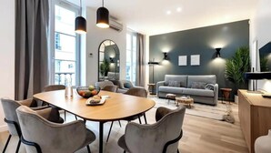 Ein modernes Wohnzimmer mit einem grauen Sofa, einem Esstisch mit Stühlen und einem großen Spiegel.