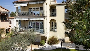 A two-story building with balconies, a garden, and a clear sky. - Graceful Apartment in Nature (Porec)