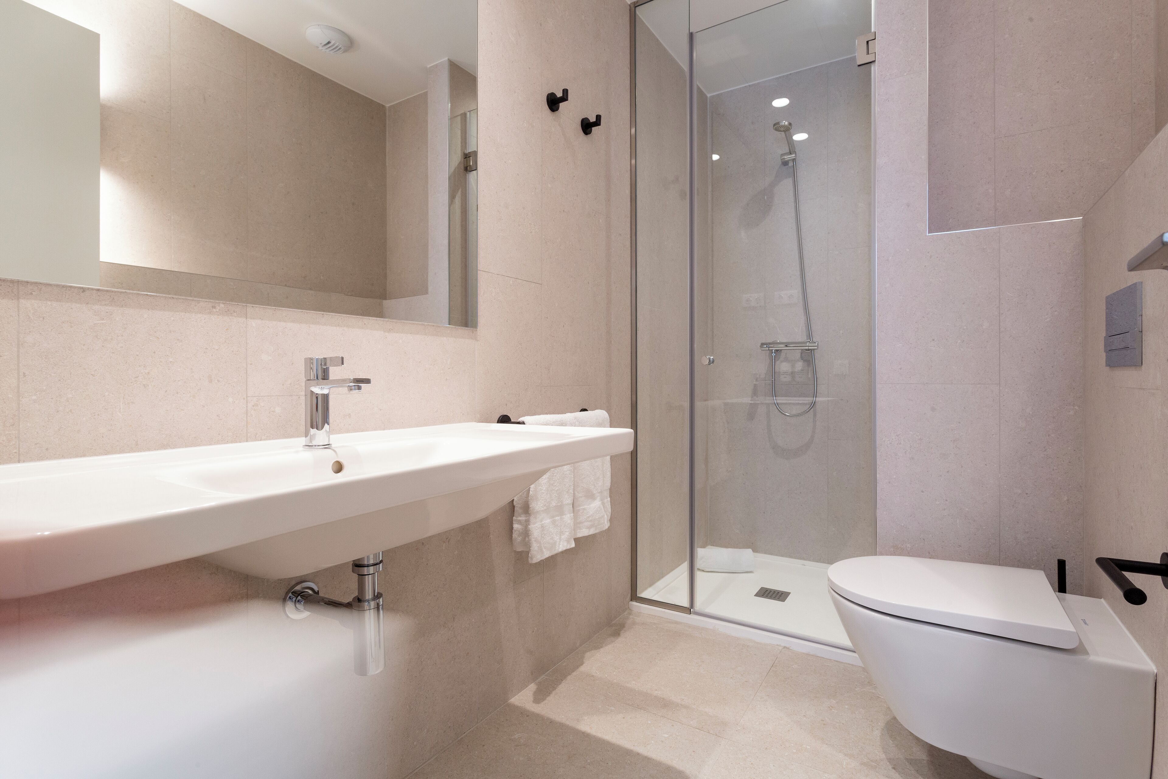 Un baño moderno con un lavamanos grande, un inodoro y una ducha con mampara de vidrio.