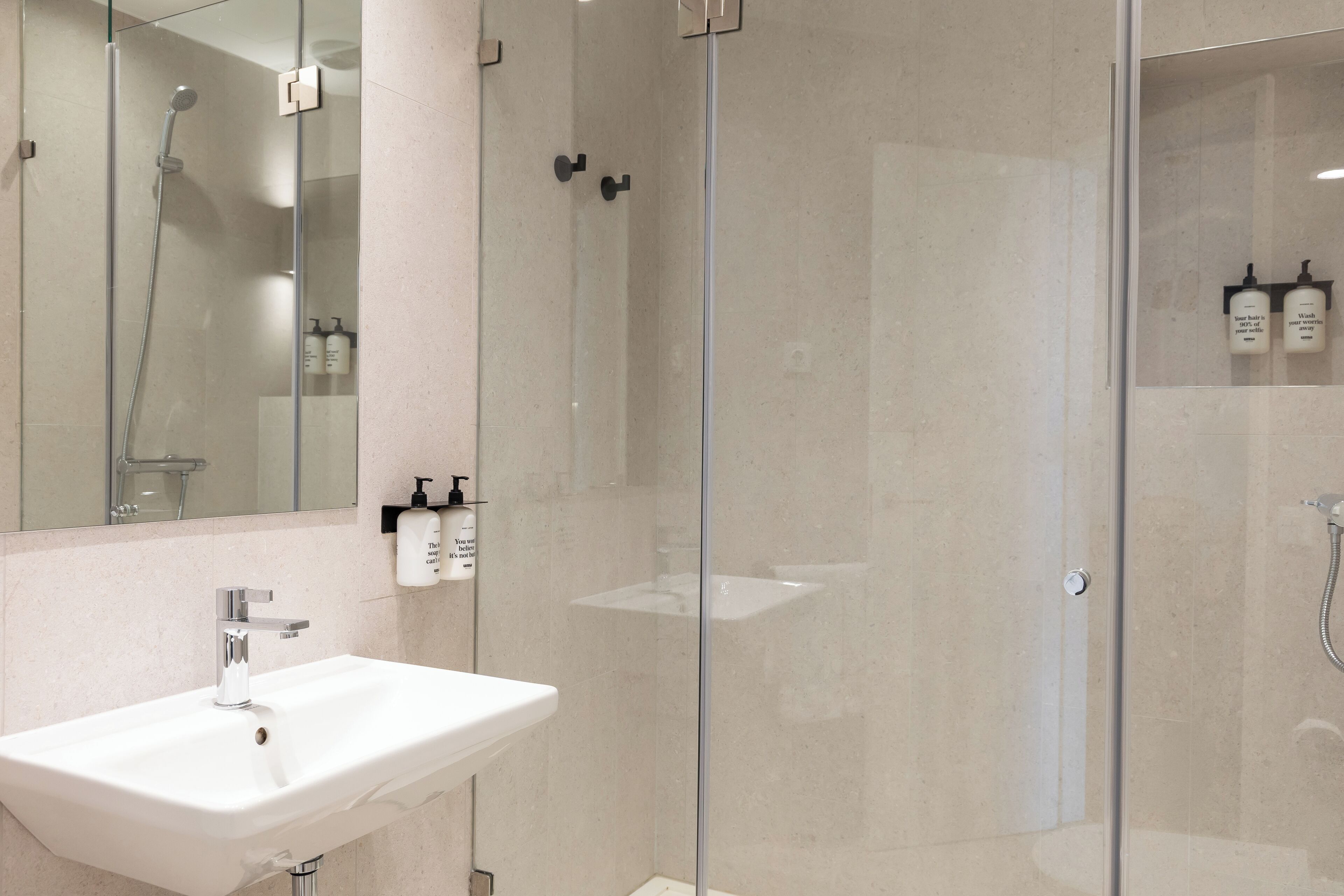 A modern bathroom with a glass-enclosed shower, a white sink, and a mirror.