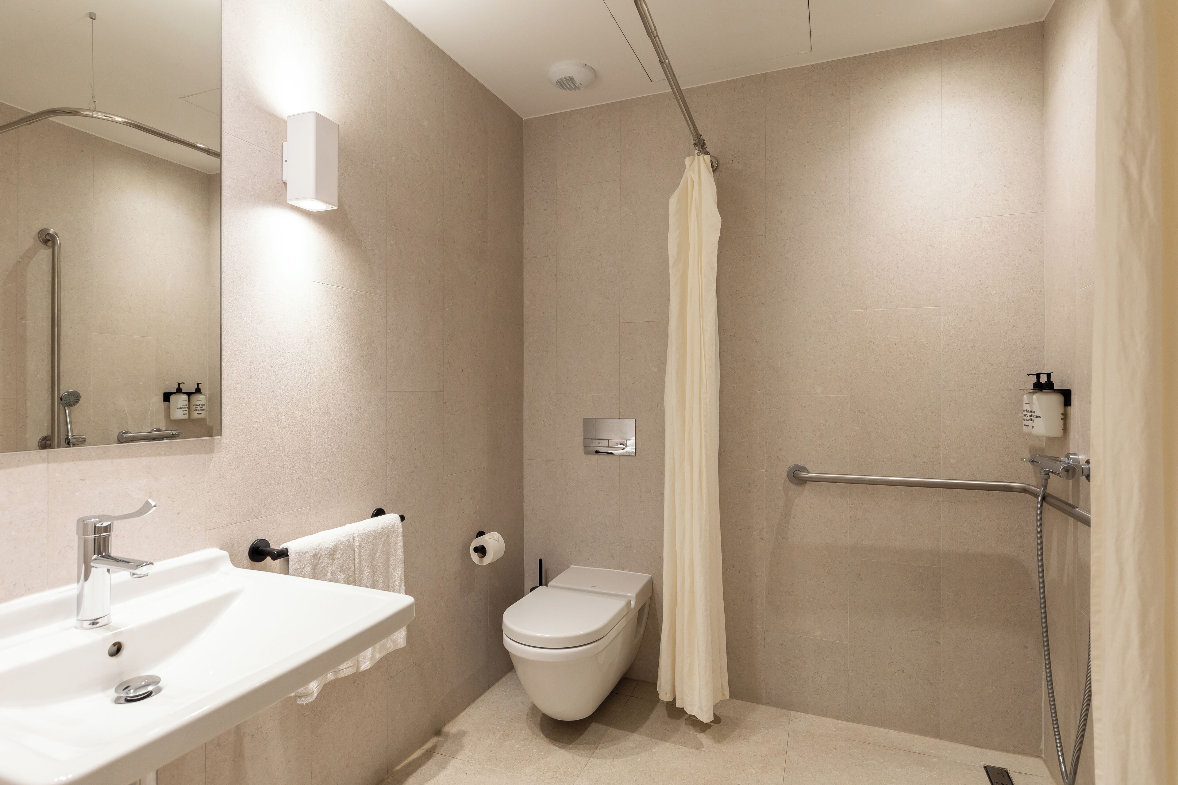 Une salle de bain moderne équipée d’un lavabo, de toilettes, d’une douche et d’un miroir.