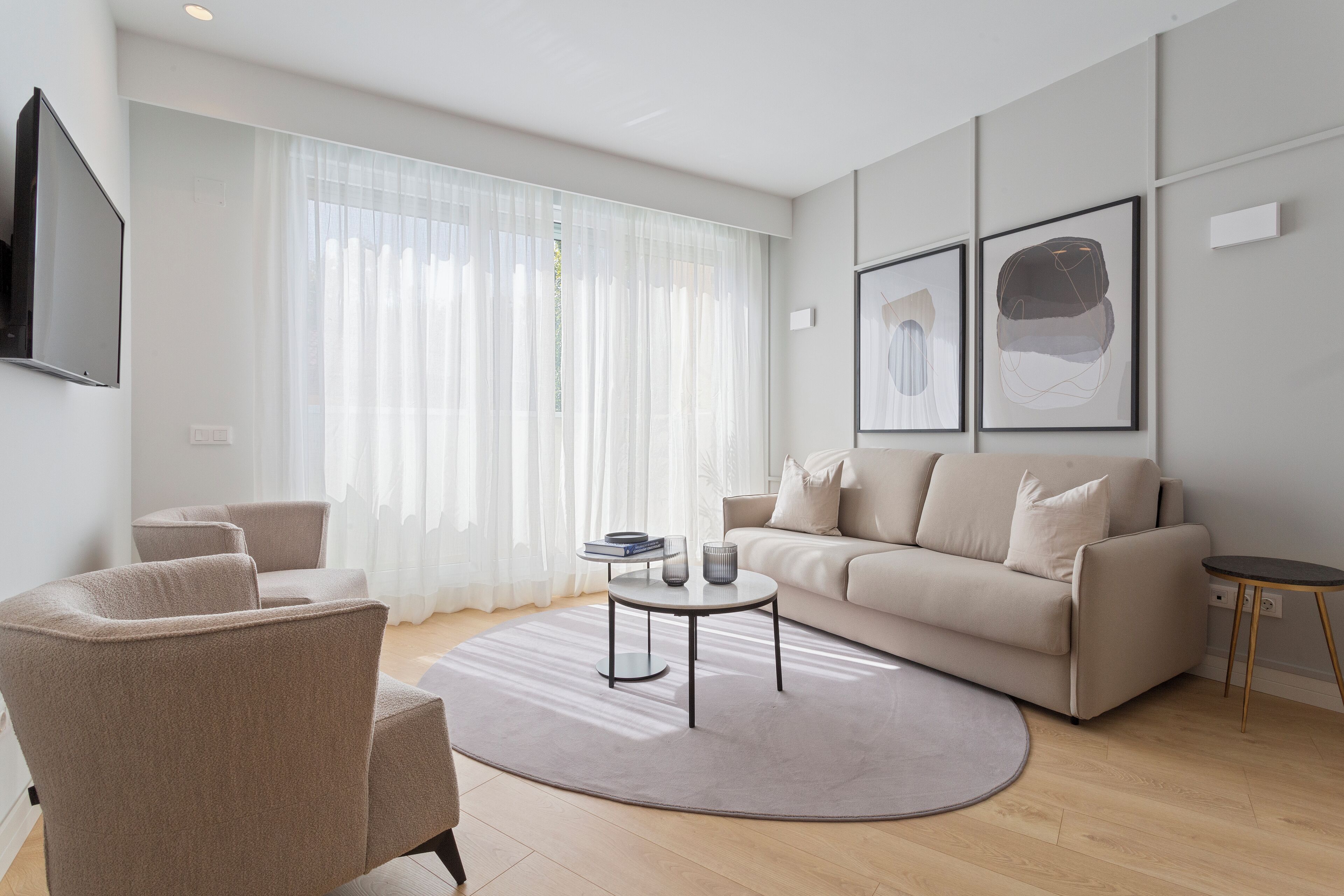 Una sala de estar moderna con un sofá, sillones, una mesa de centro y un televisor montado en la pared.