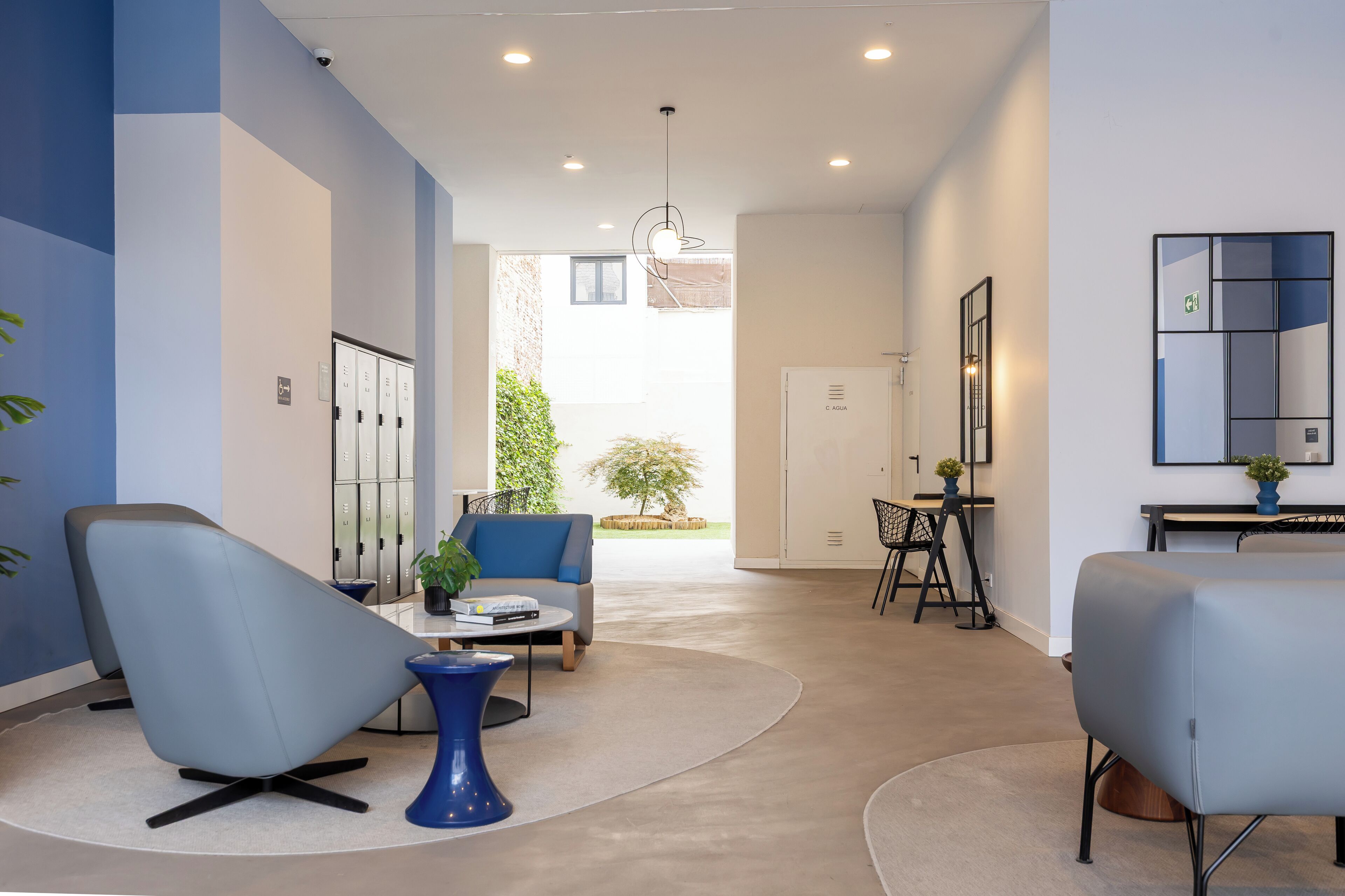 Un hall d’hôtel moderne doté d’un espace salon, d’un comptoir d’accueil et offrant une vue sur l’extérieur.