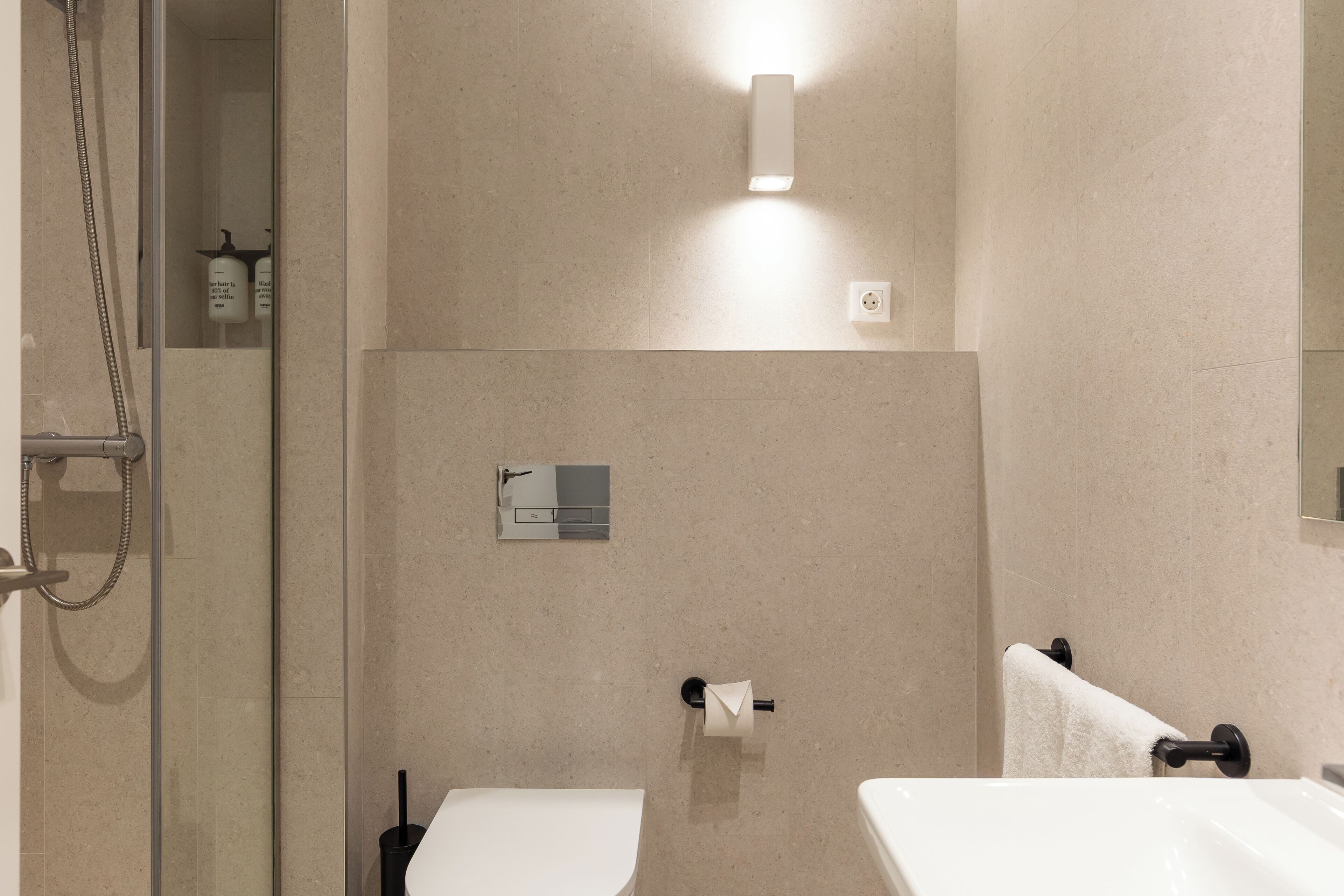 Ein modernes Badezimmer mit einer Duschkabine aus Glas, einer Toilette und einem Waschbecken.