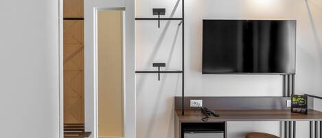 Hotelkamer met een bed, bureau met stoel, televisie, minibar en deur naar een badkamer.