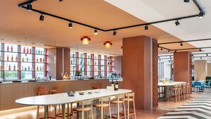 Un espace bar moderne doté d’un long comptoir, de nombreux tabourets et d’une variété de bouteilles exposées sur des étagères.