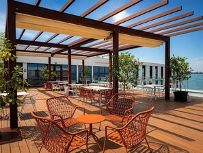 An outdoor seating area with tables and chairs, overlooking a body of water. - B&B HOTEL Venezia Laguna (Venice)