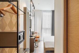 Una camera d'albergo con un letto, una scrivania con una sedia, un armadio e uno specchio.
