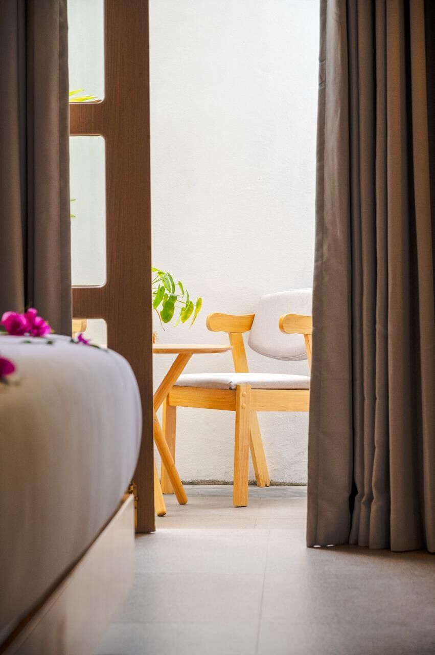 A room with a bed, a wooden chair, and a view through a window.