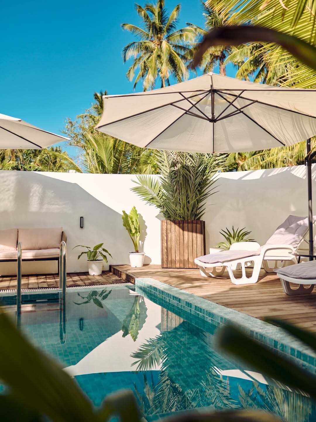 Un espace aménagé au bord de la piscine, avec des chaises longues, des parasols et une petite piscine.