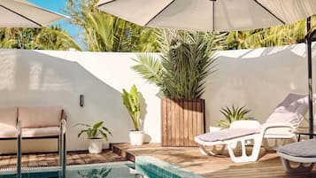 Un espace aménagé au bord de la piscine, avec des chaises longues, des parasols et une petite piscine.