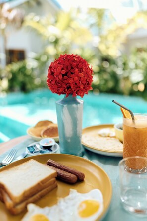 A breakfast setting with toast, eggs, sausages, and a drink by a pool. - Kondey Villas (Kondey)