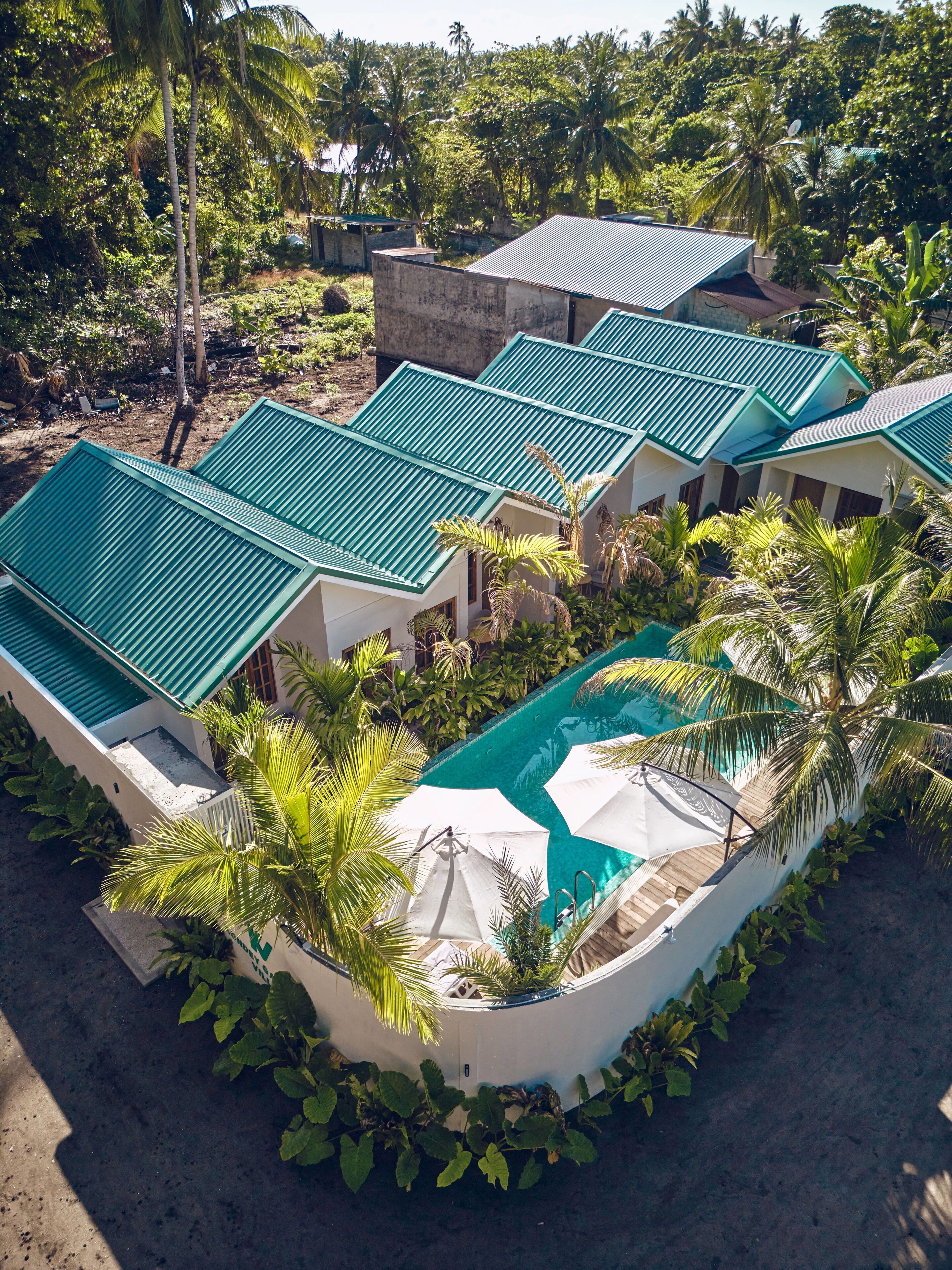 A resort with multiple buildings, a swimming pool, and lush greenery.