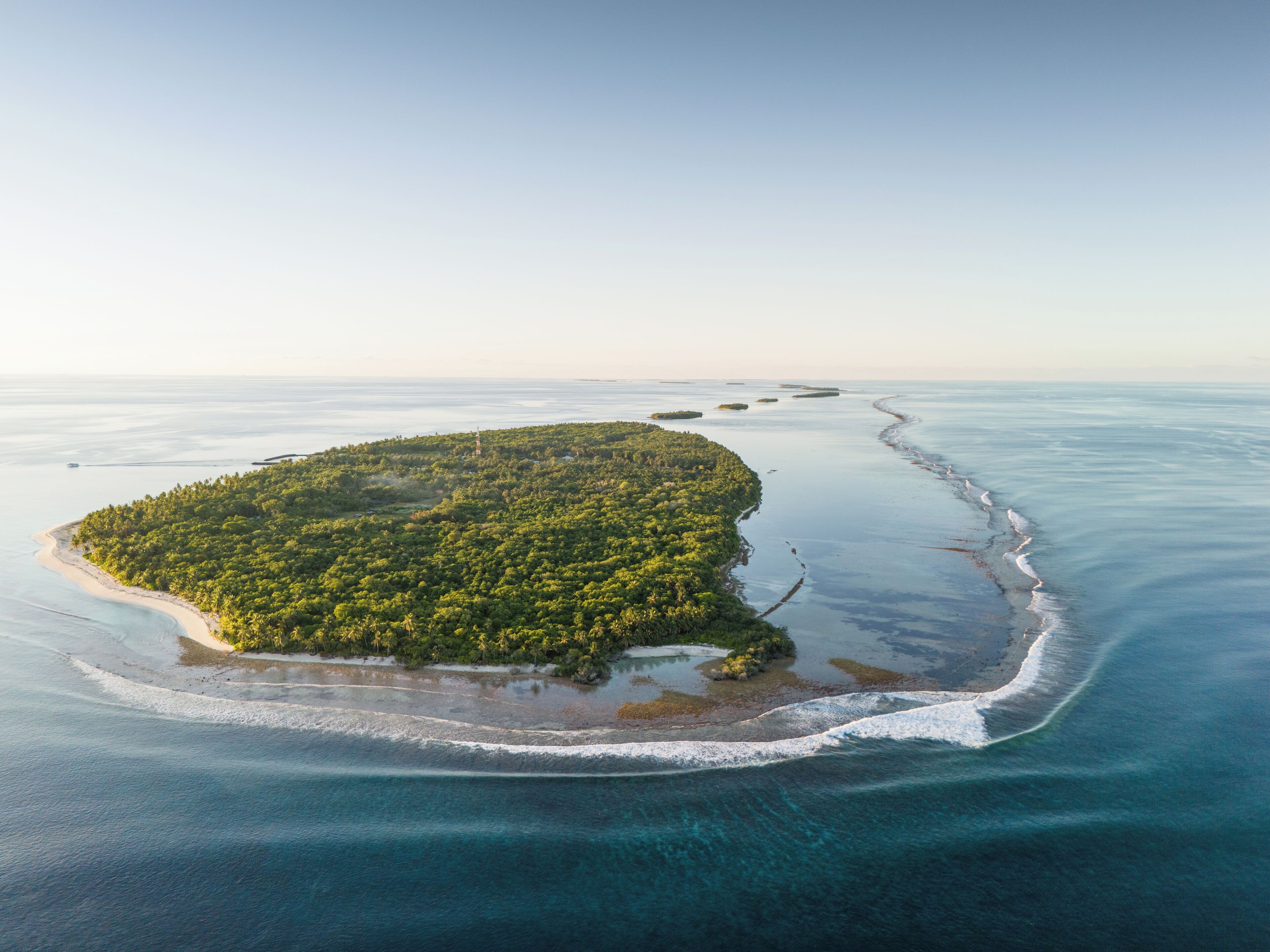 An aerial view of a tropical island with dense vegetation and a clear coastline.