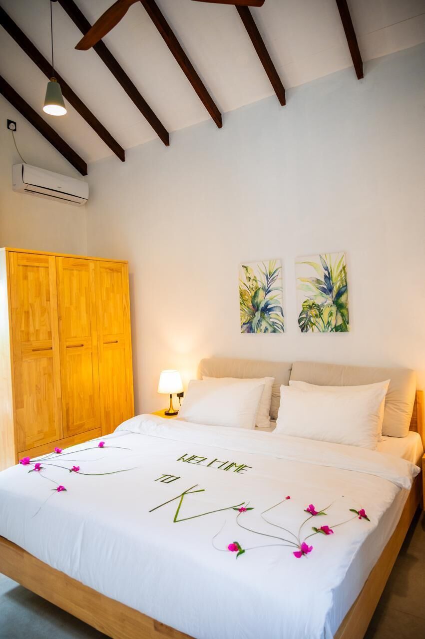 Un dormitorio con cama, armario de madera, aire acondicionado instalado en la pared y dos obras de arte en la pared.
