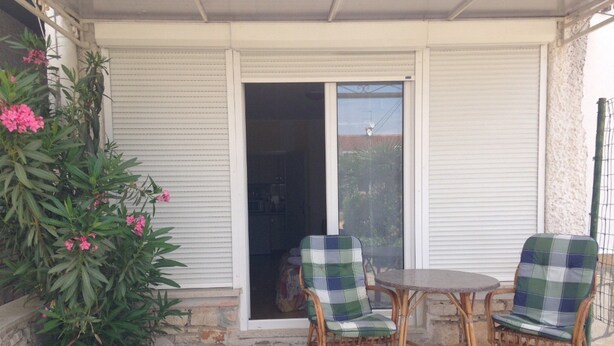 A covered patio with two wicker chairs and a small round table. - Beautiful Apartment With View (Porec)