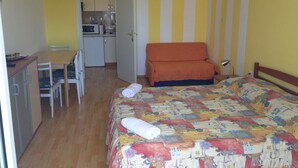 A compact room with a bed, a desk, and a kitchenette. - Beautiful Apartment With View (Porec)