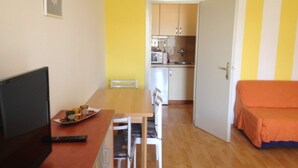 A compact living space with a dining area, kitchenette, and a bed. - Beautiful Apartment With View (Porec)