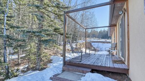 Eine Holzterrasse mit Glasverkleidung, Sitzgelegenheiten im Freien und einem mit Schnee bedeckten Boden.