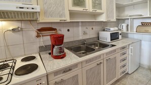 Eine Küche mit weißen Schränken, einer roten Bosch-Kaffeemaschine, einer Mikrowelle und einem Gasherd.