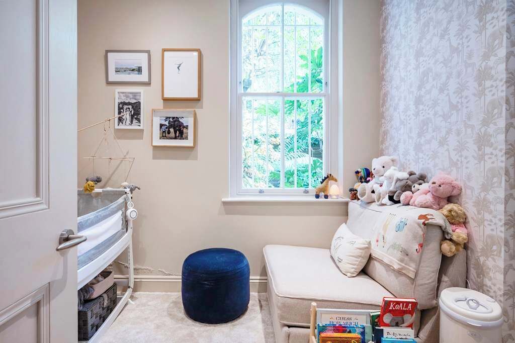 Une pièce chaleureuse avec une fenêtre, un canapé, une bibliothèque et une collection de nounours.