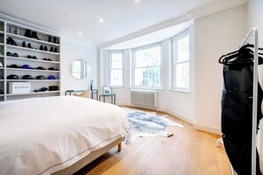Une chambre avec un grand lit, un porte-chaussures, un radiateur et une fenêtre.