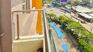 A high-rise building with a balcony overlooking a busy street and other high-rise buildings. - Flamingo: 2BHK AC Flat, Near Phoenix Mall Wakad (Pimpri-Chinchwad)