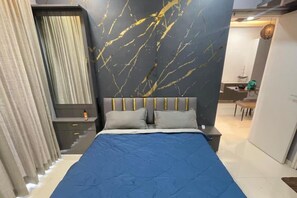 Un dormitorio con cama, mesita de noche, cómoda y pared con diseño que imita el mármol.