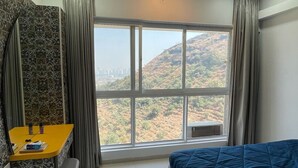 Un dormitorio con cama, escritorio y vistas a un paisaje montañoso.