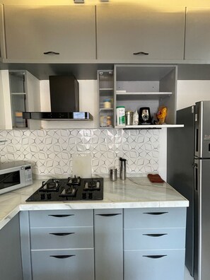 Una cocina moderna con estufa a gas, microondas, refrigerador de acero inoxidable y armarios empotrados.