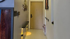 Un pasillo moderno con una puerta de madera, un banco, una lámpara de pared y una puerta con interruptor de luz.