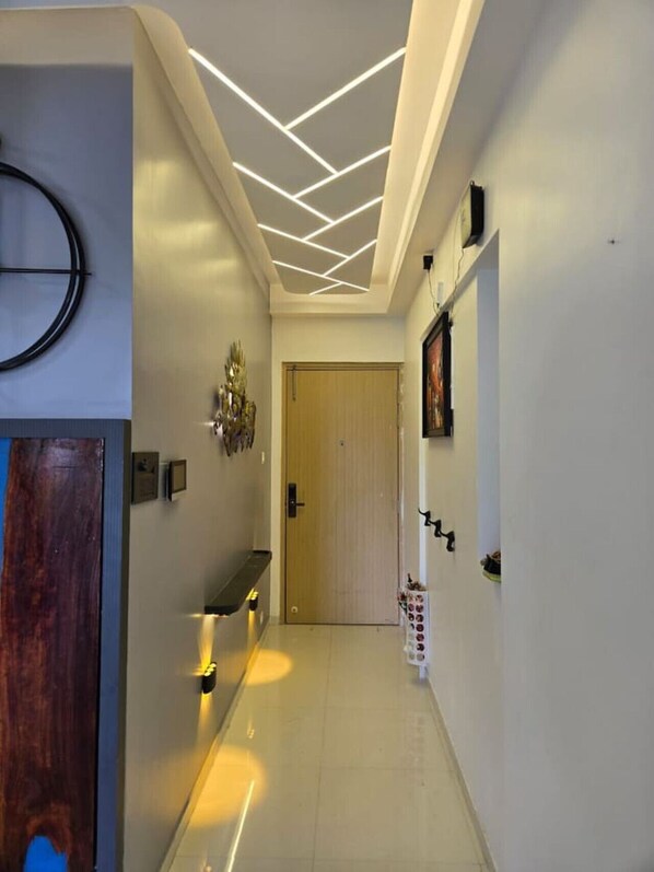 A modern hallway with a wooden door, a bench, a wall-mounted light fixture, and a door with a light switch.