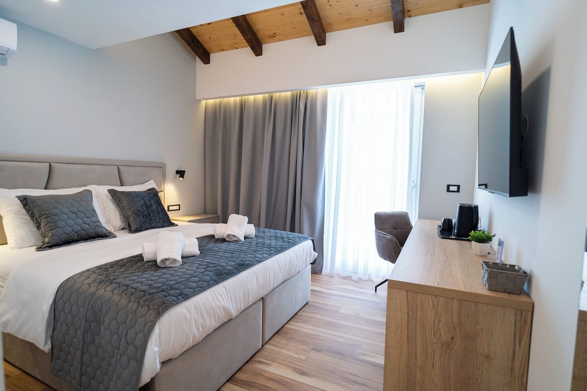 A modern hotel room with a large bed, a desk, and a TV.