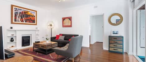 Una sala de estar moderna con chimenea, un sillón gris, una mesa de centro y un cuadro grande en la pared.